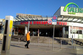 Hausmeisterservice Bauer Referenzen München - Mann mit oranger Jacke vor Eingang eines Einkaufszentrum