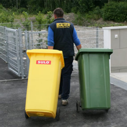 Hausmeisterservice Bauer - Mann mit einer gelben und grünen Mülltonne